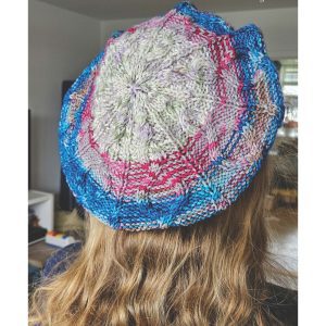 Forside billede til Lovebird Beret, som viser en forskelligt farvet beret med et smukt kabelmønster, som former et hjerte foran og snirkler sig op over skyggen og bliver mindre.